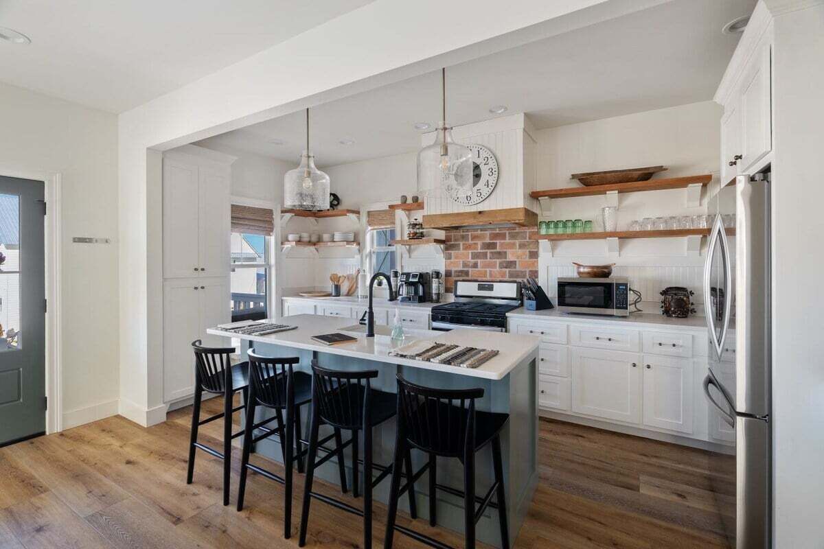 Una cocina moderna con una isla central, taburetes de bar y un refrigerador.