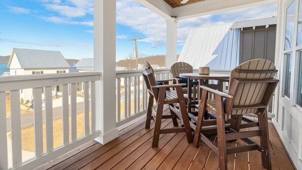 A covered outdoor area with a wooden deck, a table, two chairs, and a ceiling fan.