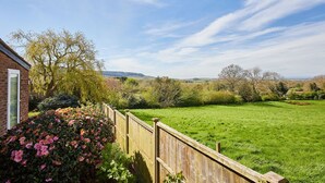 Il s’agit d’une propriété résidentielle dotée d’une pelouse bien entretenue, d’une clôture en bois et offrant une vue sur un paysage rural.