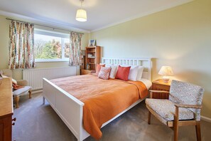 A bedroom with a bed, a chair, a nightstand, a lamp, a bookshelf, and a window with curtains. - Host & Stay | Manifold (Northallerton)