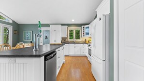 Una cocina moderna con armarios blancos, una isla central y un lavavajillas integrado.