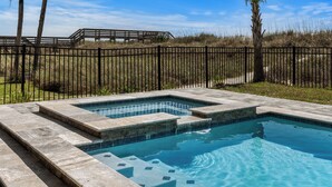 Et rektangulært swimmingpool med stenvæg og træterrasse i baggrunden.
