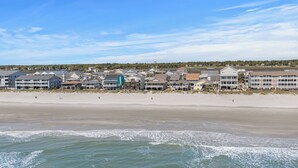 Et hotel ved stranden med flere bygninger, en sandstrand og havnebølger.