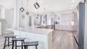 A modern kitchen with a large island, white cabinetry, and pendant lighting.