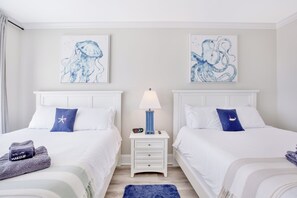A hotel room with two beds, a nightstand with a lamp, and artwork on the walls. - Serenity Hideaway: Oceanfront w/ Pool & Stunning Views (North Myrtle Beach)
