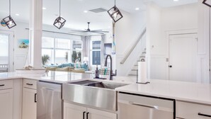 A modern kitchen with stainless steel appliances, white cabinetry, and a large window overlooking a balcony.