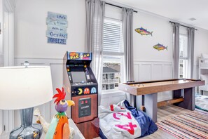 A room with a pool table, arcade games, and a view of the city. - Serenity Hideaway: Oceanfront w/ Pool & Stunning Views (North Myrtle Beach)