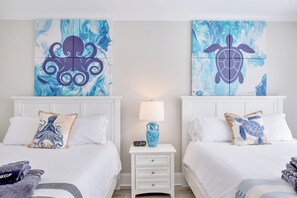 A hotel room with two beds, white bedding, and artwork depicting an octopus and a turtle. - Serenity Hideaway: Oceanfront w/ Pool & Stunning Views (North Myrtle Beach)
