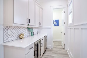 A kitchen with white cabinets, a white countertop, and a tiled backsplash. - Serenity Hideaway: Oceanfront w/ Pool & Stunning Views (North Myrtle Beach)