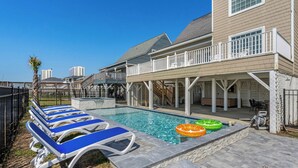 A pool area with lounge chairs, a covered deck, and a stone border.