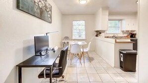 Cocina compacta con comedor, un pequeño contenedor de basura y un ventanal que proporciona luz natural.