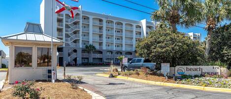 A multi-story hotel with a beach house sign, a no parking sign, and a tow away zone sign.