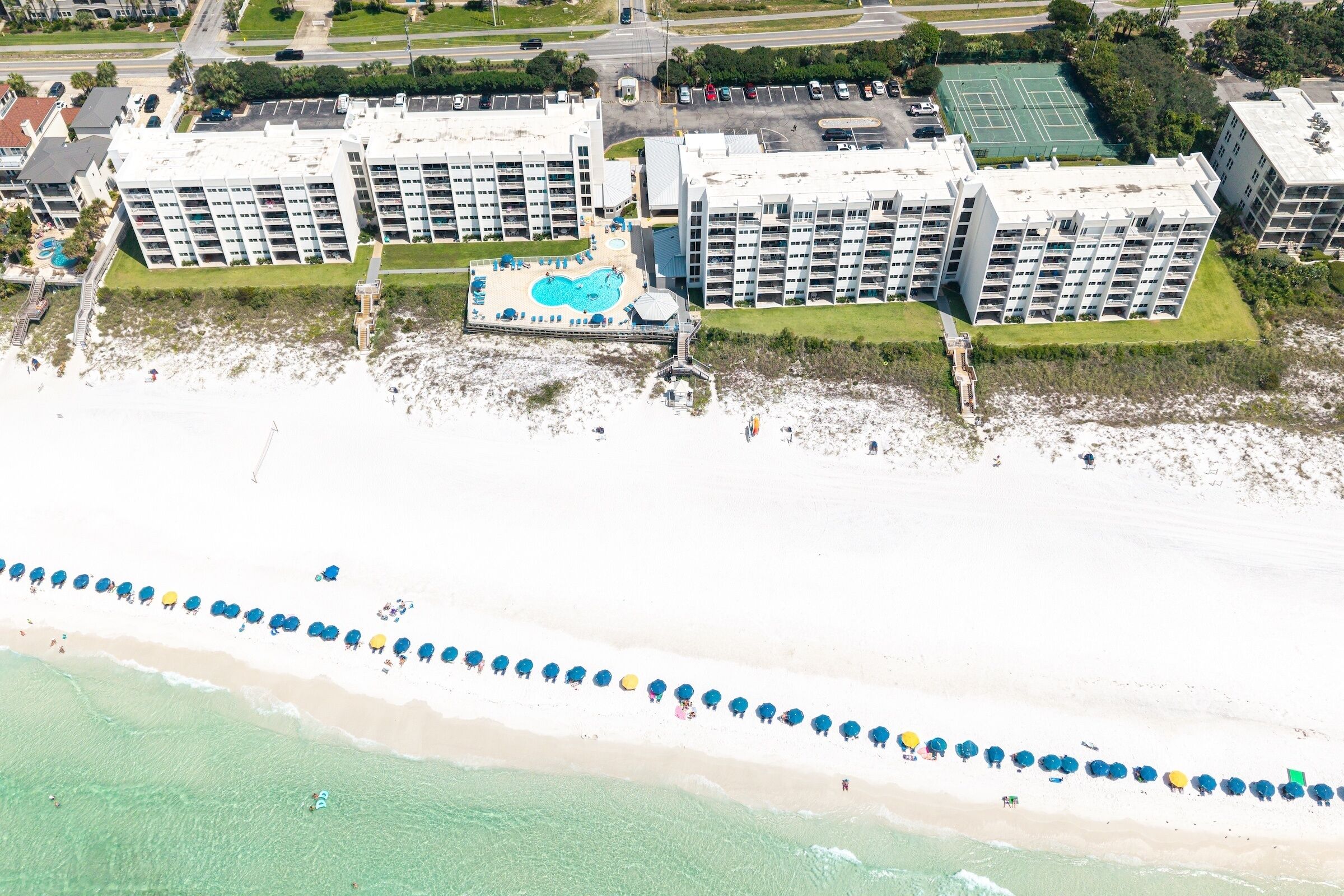 Un hotel frente al mar con varias edificaciones, una playa y una zona de piscina.
