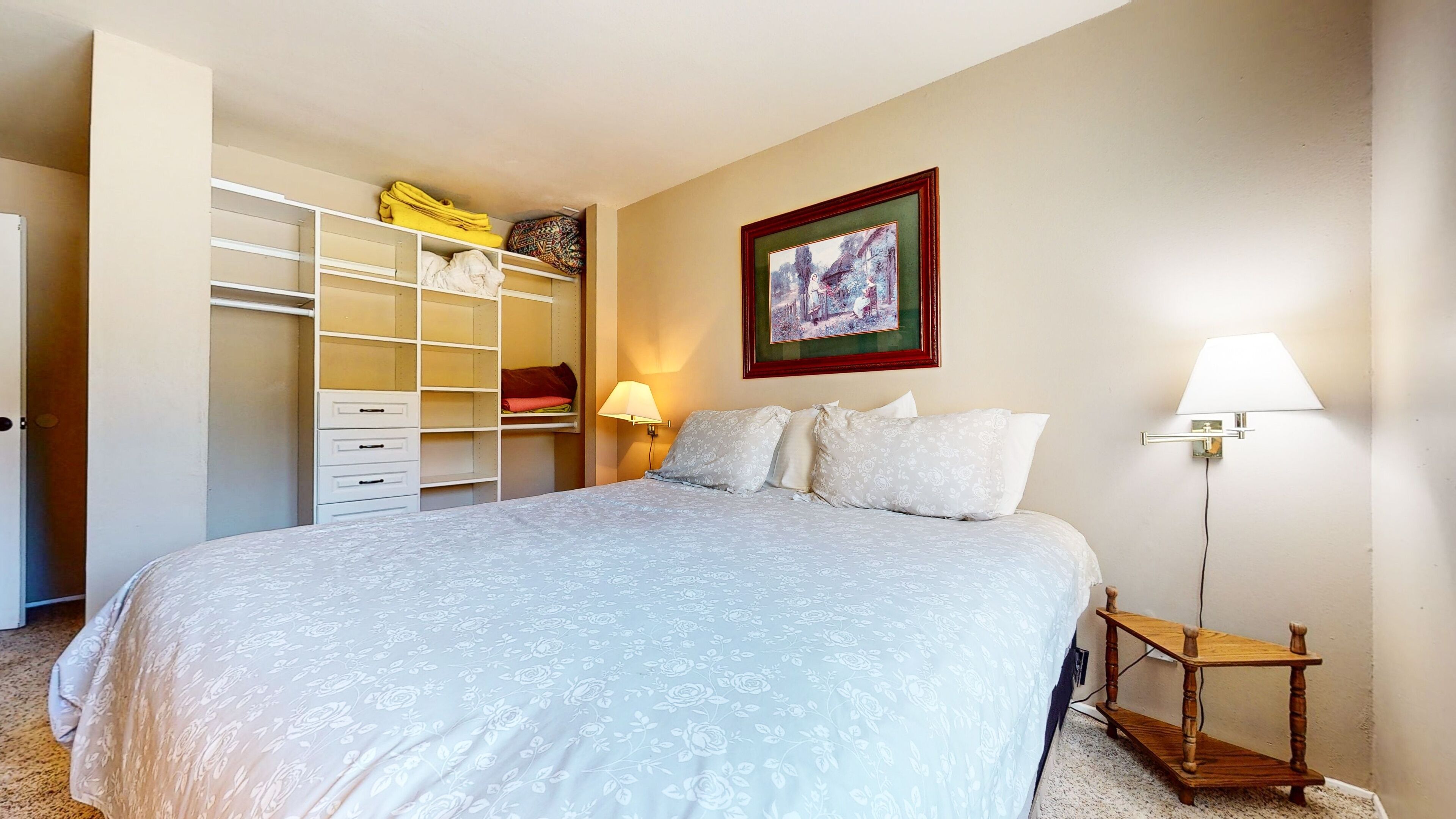 A bedroom with a bed, a wardrobe, a bedside table, and a lamp.