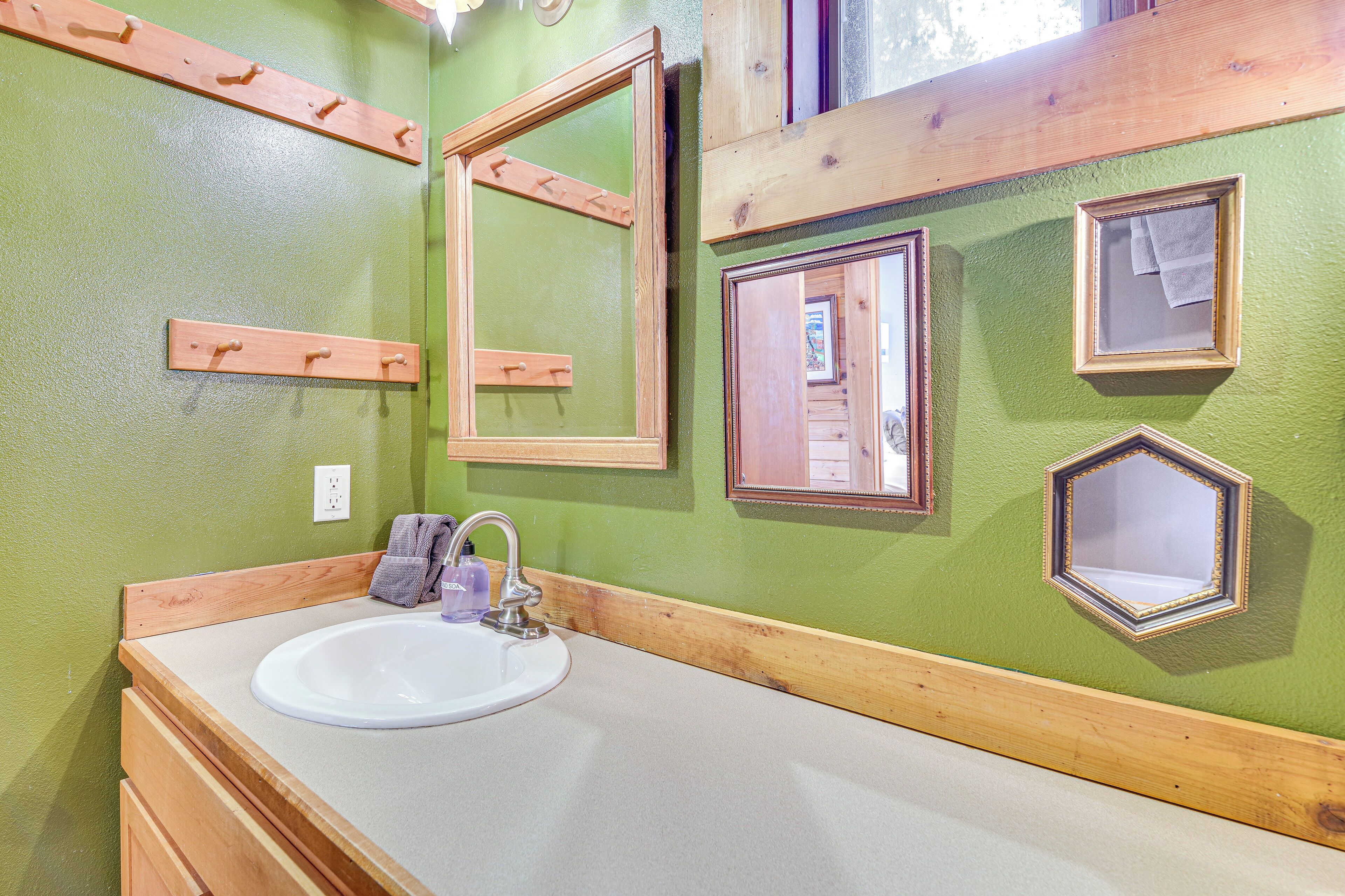 Un baño con tocador de madera, lavamanos y espejos.