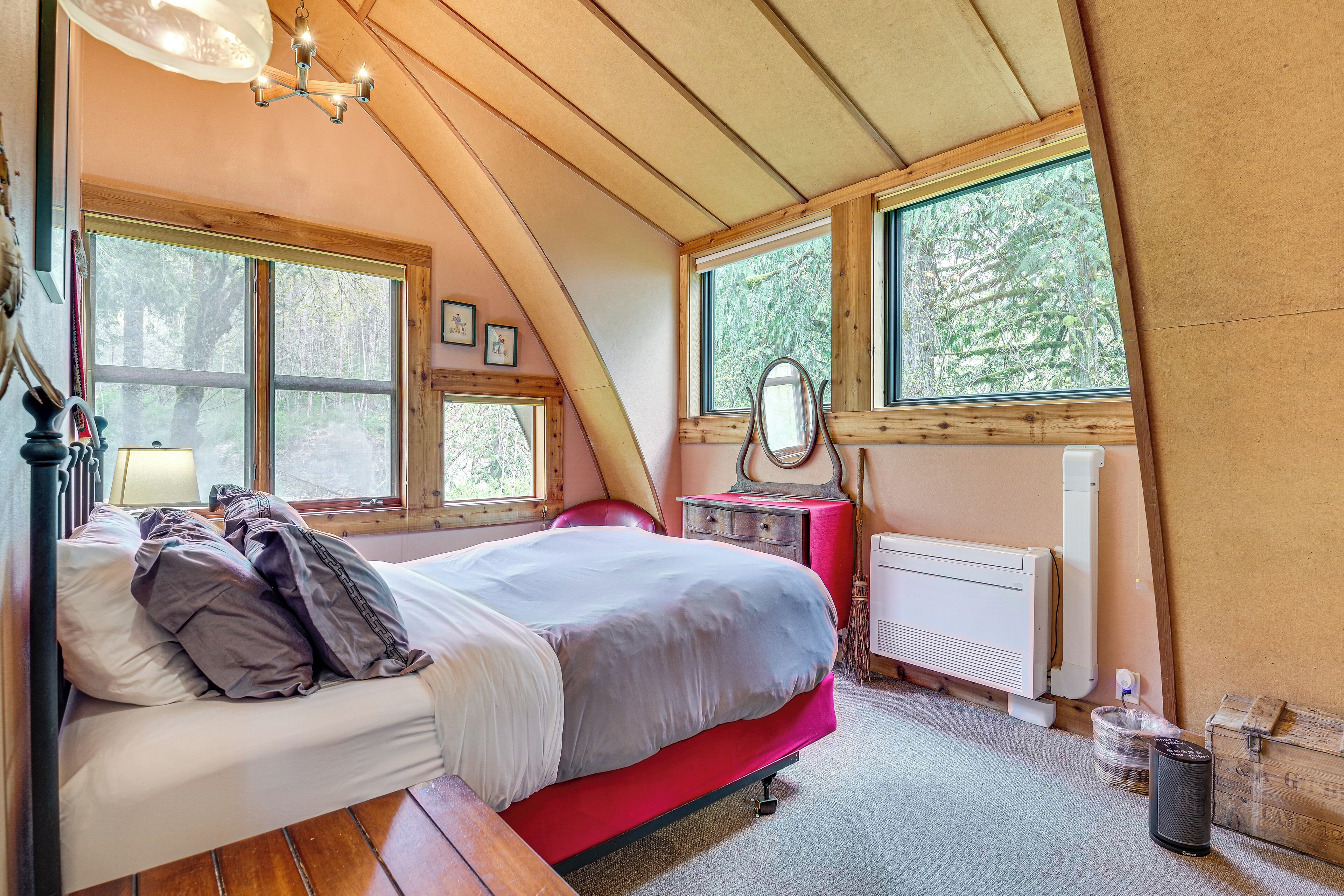 A bedroom with a bed, dresser, and large windows.