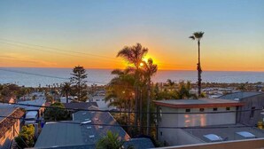 Ein Wohngebiet mit Häusern, einer Palme und einem Sonnenuntergang über dem Meer.