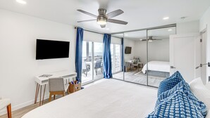Ein modernes Hotelzimmer mit einem großen Bett, einem Schreibtisch, einem Sessel, einem Fernseher und einem Balkon mit Blick.