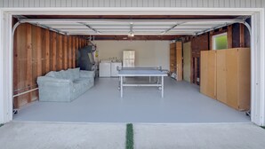 Eine Garage mit Tischtennisplatte, einer Couch und Stauraumschränken.