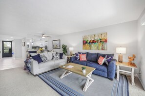 A modern living room with a sofa, coffee table, and a painting on the wall.