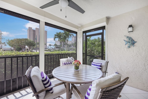 A balcony with a round table, chairs, and a decorative fish wall art piece.