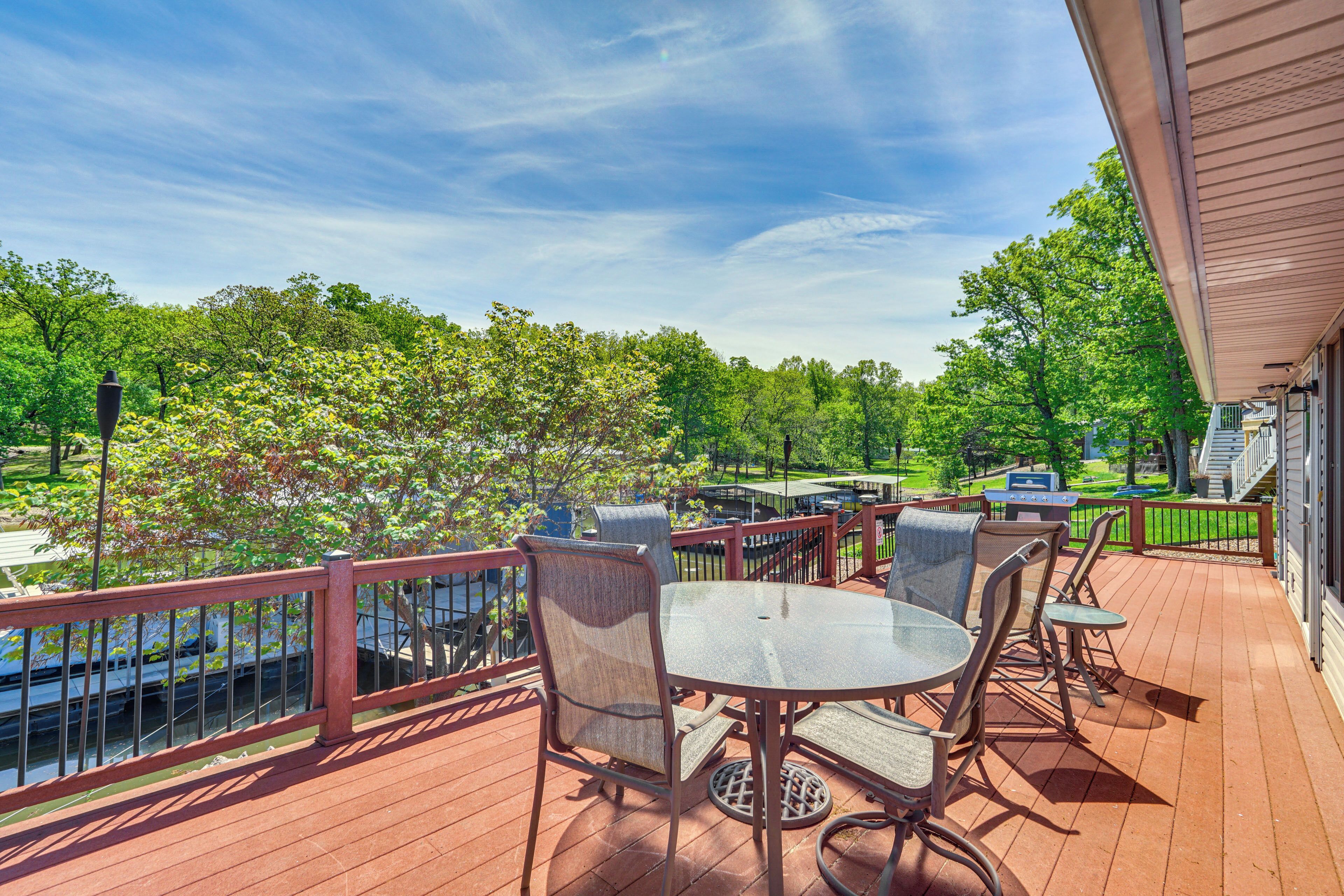 A wooden deck with outdoor furniture, a view of a river, and a covered area with stairs.