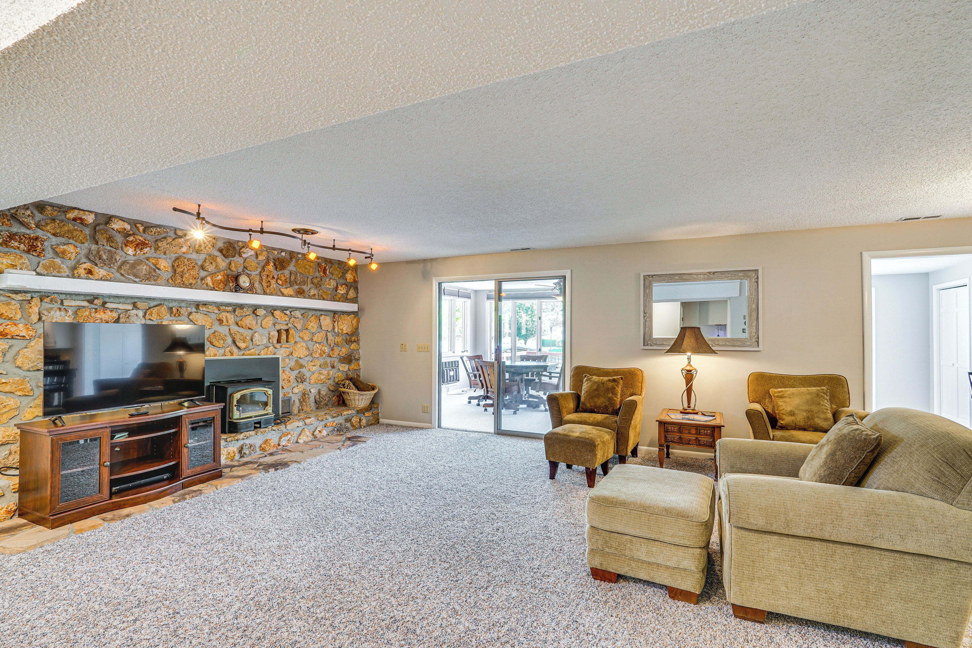 A living room with a stone wall, a television, a fireplace, and a large window.