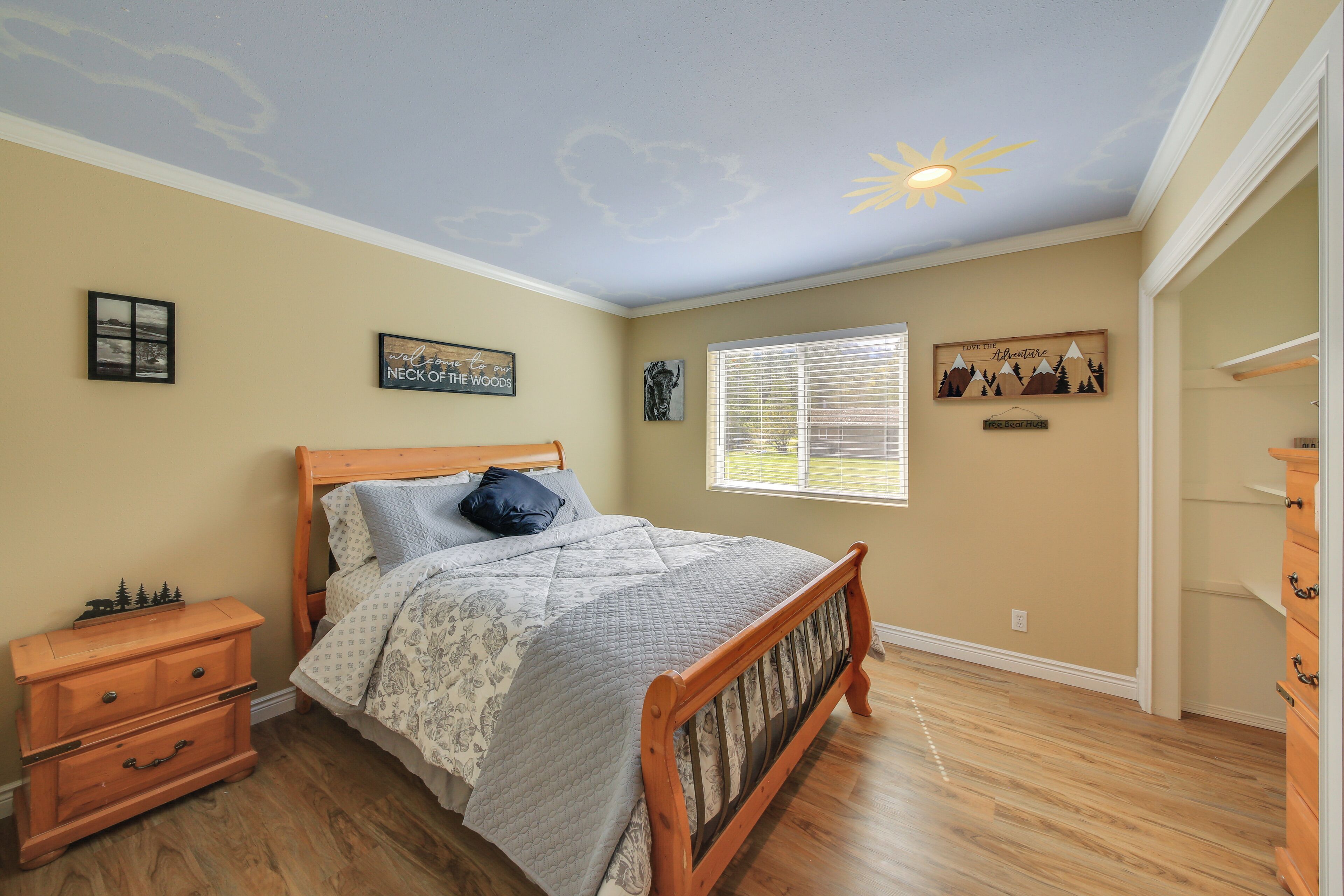 A bedroom with a wooden bed, a dresser, and a window with blinds.