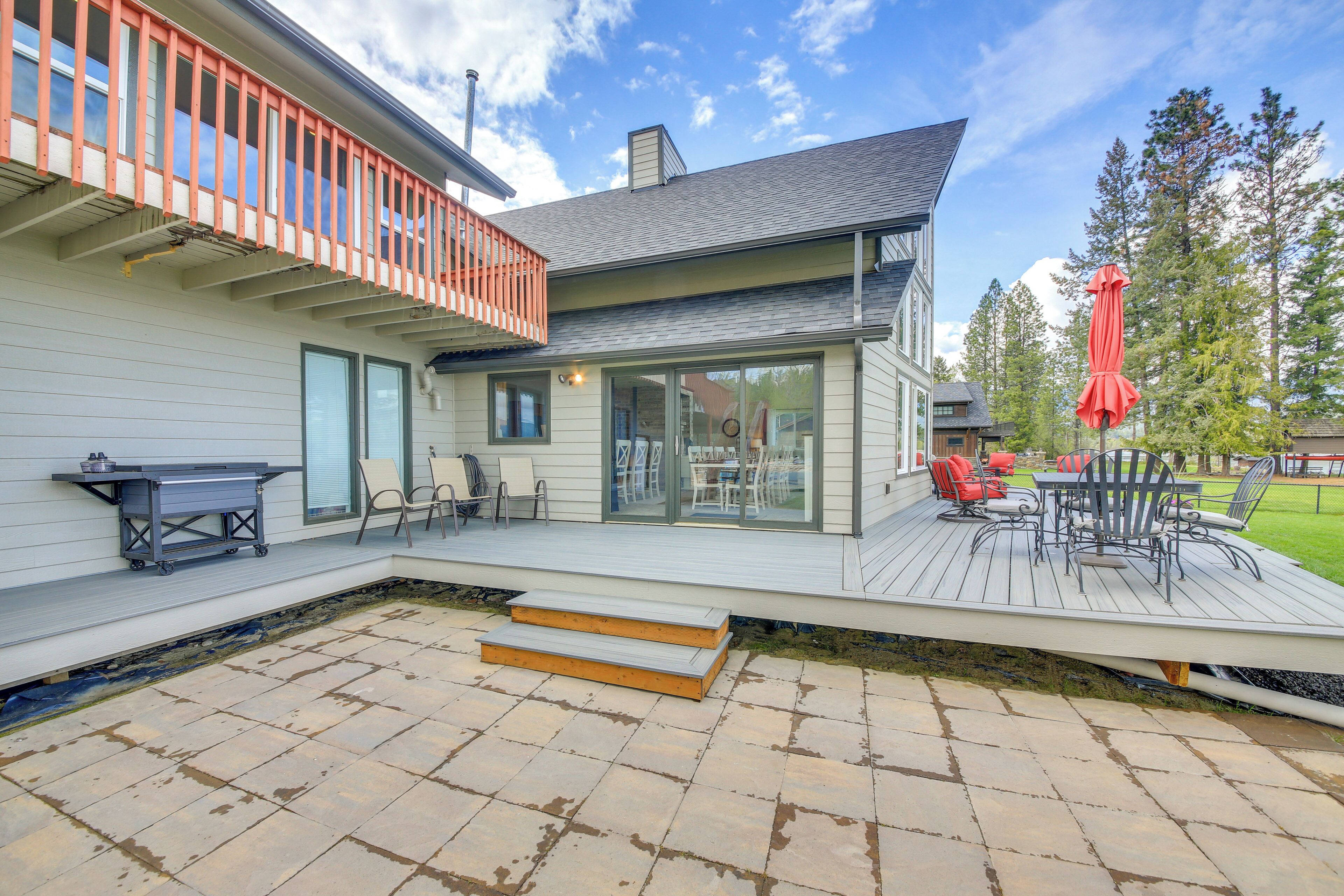 A modern house with a deck, outdoor furniture, and a grill.