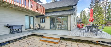 A modern house with a deck, outdoor furniture, and a grill.