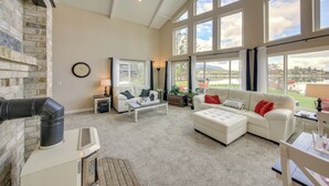 A spacious living room with a fireplace, large windows, and a view of the outdoors. - Beachfront Sagle Retreat w/ Boat Dock & Lift (Sagle)