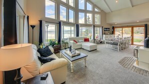 A spacious living room with a high ceiling, large windows, and a view of the outdoors. - Beachfront Sagle Retreat w/ Boat Dock & Lift (Sagle)