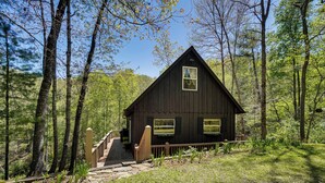 A rustic cabin with a stone staircase leading to a wooden deck, surrounded by dense forest. - Fire Pit + Community Perks: Murphy Family Cabin! (Murphy)