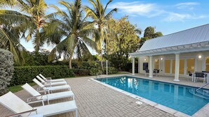 A pool area with lounge chairs and a covered seating area. - Cayman Blu 2 Bedroom Waterfront Condo (Grand Harbour)