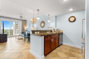 A modern kitchen with a central island, pendant lighting, and a view to the outside.