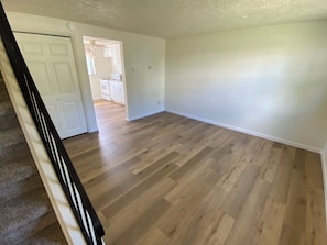 A spacious room with hardwood flooring and white walls.