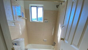 Une petite salle de bain comprenant des toilettes, une baignoire et une fenêtre.