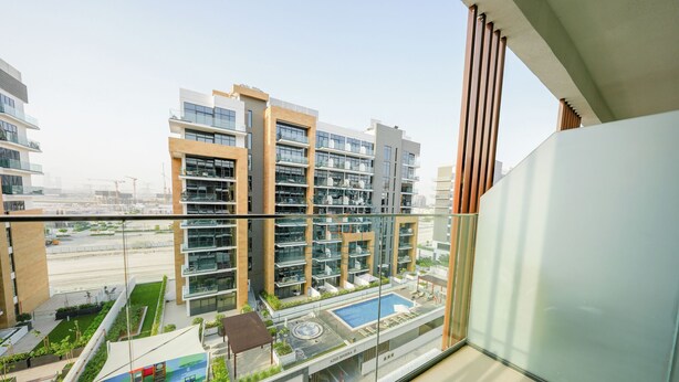 Un immeuble résidentiel moderne doté de nombreux balcons, d’une piscine sur le toit et d’un espace paysager.