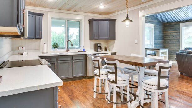 A modern kitchen with grey cabinets, a wooden island, and bar stools. - 'dularge Copper Landing' - Steps to Falgout Marina (Theriot)