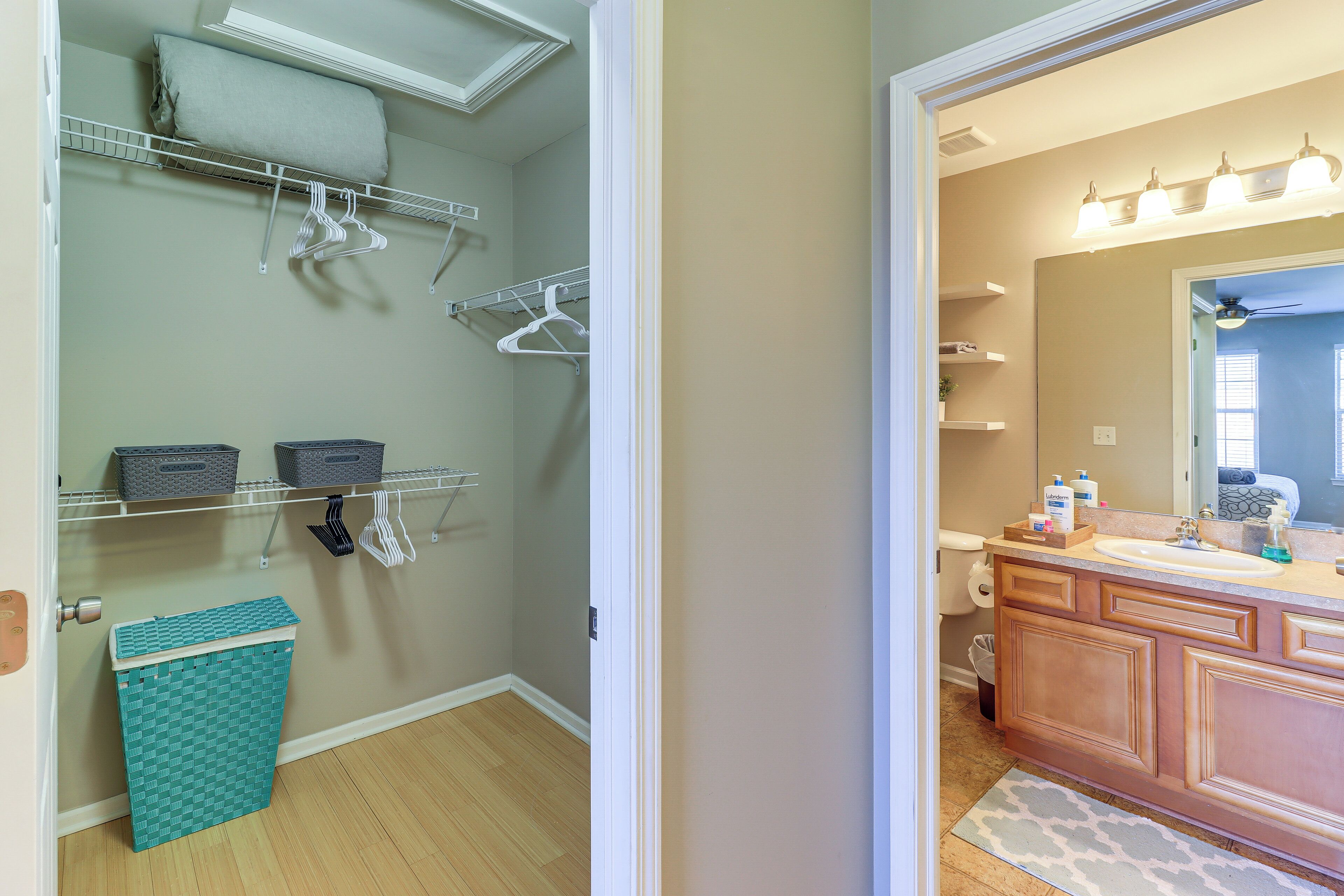 A bathroom with a wooden vanity, a mirror, and a sink. There are storage shelves above the vanity and a small trash bin next to the toilet.
