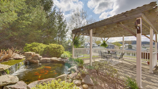 A covered patio with outdoor furniture, a koi pond, and surrounding greenery. - Pet-friendly New Kensington Apt w/ Shared Perks (New Kensington)