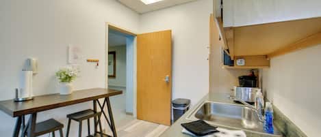 Une cuisine compacte avec un tabouret de bar en bois, un évier et un plan de travail.