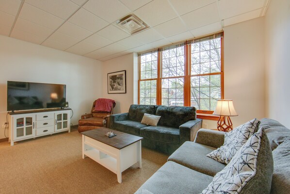 A living room with a television, sofa, and a window with a view of trees. - 20 Mi to Dtwn Pittsburgh: Pet-friendly Apartment (New Kensington)