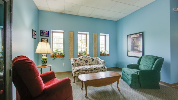 A living room with a red armchair, a floral sofa, a green armchair, a wooden coffee table, and a lamp on a side table. - 20 Mi to Dtwn Pittsburgh: Pet-friendly Apartment (New Kensington)