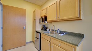 A kitchen with wooden cabinets, a stainless steel refrigerator, a microwave, and a sink. - Day Trip to Pittsburgh: Comfy New Kensington Apt! (New Kensington)