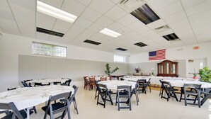 A large room with multiple tables set for dining, a flag on the wall, and an exit sign. - Day Trip to Pittsburgh: Comfy New Kensington Apt! (New Kensington)