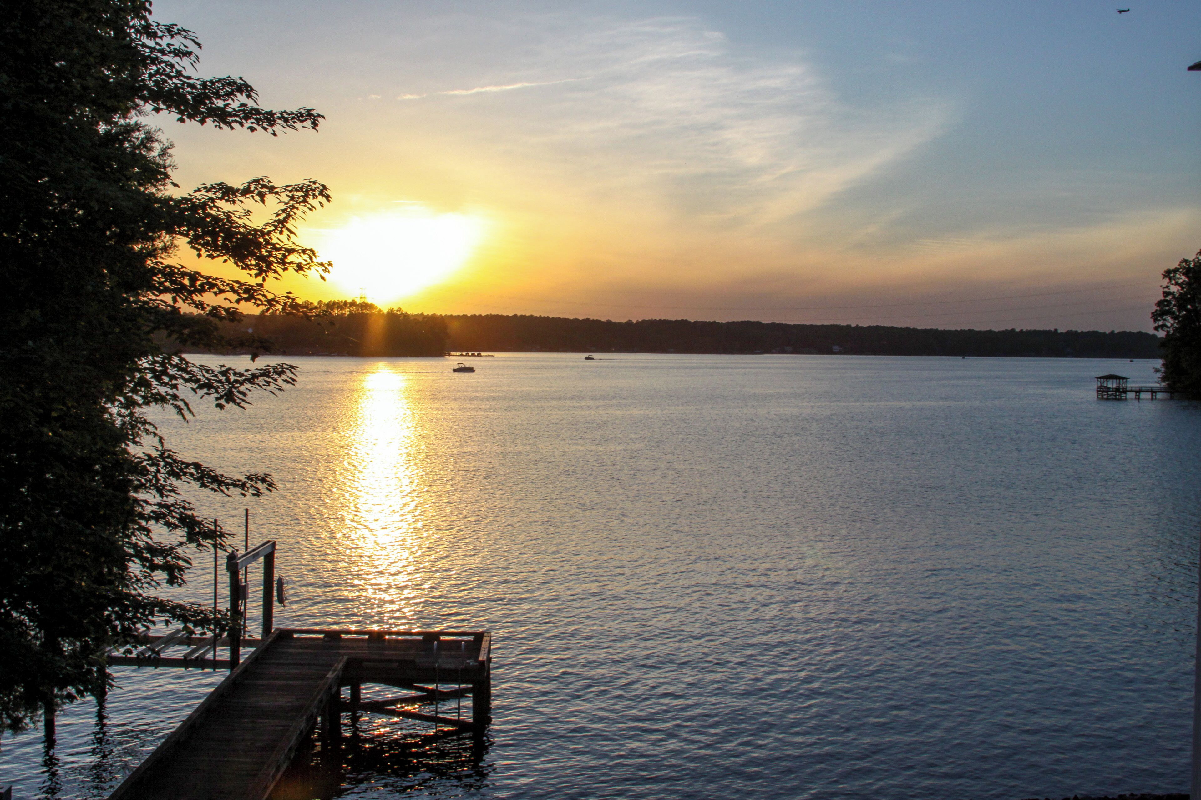 Un atardecer sobre un lago tranquilo con un muelle de madera que se adentra en el agua.