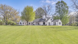 A large, single-story house with a spacious lawn and multiple windows.