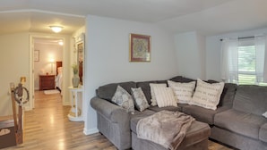 A living room with a gray sectional sofa, a white side table, and a wooden floor. - 5 Mi to Columbia: Pet-friendly Culleoka Home (Culleoka)