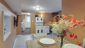 A dining area with a wooden table set for two, a vase with flowers, and a kitchen in the background. - 5 Mi to Columbia: Pet-friendly Culleoka Home (Culleoka)